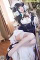 A woman in a maid outfit sitting on a chair.