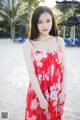 A woman in a red dress standing on a beach.