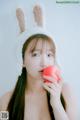 A woman in bunny ears eating an apple.