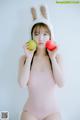 A woman in a bunny hat holding two apples.