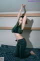 A woman with green hair is posing on a bed.