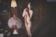 A naked woman standing in a living room holding an umbrella.