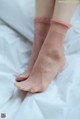 A woman's feet in pink socks on a bed.