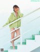 A woman in a green sweater is standing on some stairs.