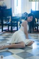 A woman in a white dress sitting on the floor.