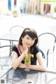 A woman sitting at a table with a drink in her hand.