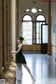 A young ballerina in a black leotard and pointe shoes.