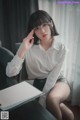 a woman sitting at a desk with a laptop and glasses