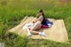 A woman sitting on top of a blanket in a field.