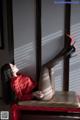 A woman in a red shirt and black stockings sitting on a red chair.