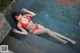 A woman in a red bikini laying on the edge of a pool.