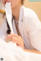 A woman in a white shirt is holding a piece of paper in her mouth.