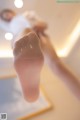 A woman in a white shirt and white socks is doing a yoga pose.