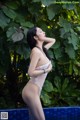 A woman in a white lingerie standing next to a pool.