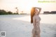 A woman in a long dress standing on a beach.