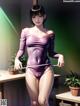 A woman in a purple bodysuit standing in a room.