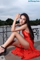 A woman in a red dress sitting on a railing.