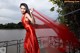 A woman in a red dress standing on a bridge.