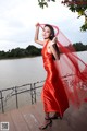 A woman in a red dress standing on a wooden dock.