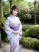 A woman in a blue and purple kimono standing in a garden.