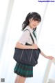 A young woman in a school uniform holding a black bag.