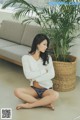 A woman sitting on the floor next to a plant.