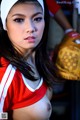 A woman in a red and white cheerleading uniform holding a baseball glove.