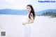 A woman in a white dress standing on a beach.