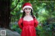 A woman in a red dress and a santa hat posing for a picture.