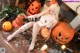 A woman sitting on the floor surrounded by pumpkins.