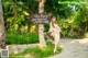 A woman in a long dress standing in front of a sign.