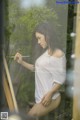 A woman in a white shirt is painting on a easel.