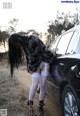 A woman leaning against a car in a field.