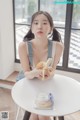 A woman sitting at a table holding a banana.