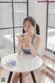 A woman sitting at a table eating a banana.