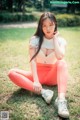 A woman sitting on the ground in a park.