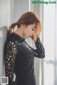 A woman in a black dress leaning against a wall.