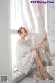 A woman in a white dress sitting on a window sill.