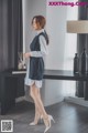 a woman standing in front of a desk wearing a dress