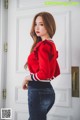 A woman in a red sweater and jeans posing for a picture.