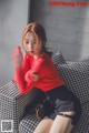 a woman sitting on top of a couch wearing a red sweater