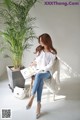 A woman sitting on a chair next to a plant.