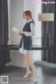 A woman standing in front of a desk holding a piece of paper.