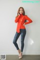 A woman in a red sweater and jeans posing for a picture.