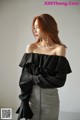 A woman wearing a black off the shoulder top with ruffles.