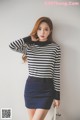 A woman wearing a black and white striped sweater and a blue skirt.