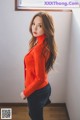 A woman in a red sweater and jeans posing for a picture.