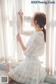 a woman in a white dress sitting on a window sill