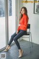 A woman sitting on a chair in front of a window.