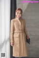 A woman wearing a beige coat with a belt.